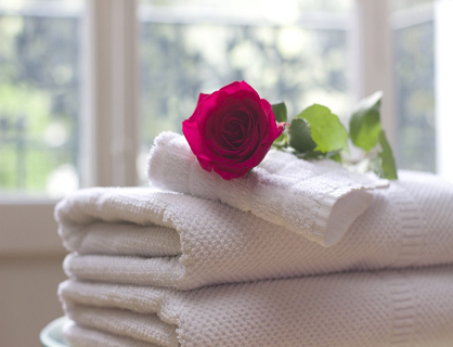 White clean towels decoration with red flower on white clean bed